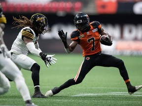 B.C. Lions' Lucky Whitehead (7) tries to run the ball past Hamilton Tiger-Cats' Tunde Adeleke during the first half of CFL football game in Vancouver, on Thursday, July 21, 2022.