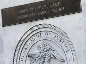 FILE - A sign for the Department of Justice Federal Bureau of Prisons is displayed at the Metropolitan Detention Center in the Brooklyn borough of New York, July 6, 2020. The Justice Department has settled a long-running lawsuit filed by a group of men rounded up in the weeks after the September 2001 attack who say they were abused in a federal lockup in New York City.