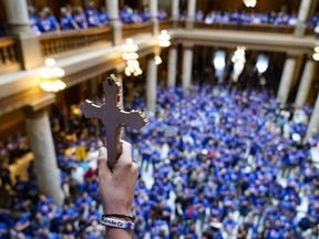 FILE - Luke Howard, of Avon, Ind., holds a crucifix aloft as anti-abortion supporters rally as the Indiana Senate Rules Committee met a Republican proposal to ban nearly all abortions in the state during a hearing at the Statehouse in Indianapolis, July 26, 2022.