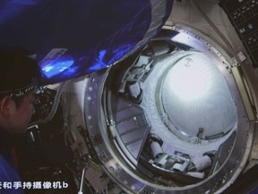 In this photo released by Xinhua News Agency, an image taken off the screen at the Beijing Aerospace Control Center shows Chinese astronaut Chen Dong opening the hatch door of the Wentian lab module on Monday, July 25, 2022. China added the laboratory to its permanent orbiting space station Monday as it moves toward completing the structure in coming months. Chinese characters on screen reads "Handheld camera b."
