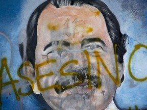 FILE - The Spanish word for "Murderer" covers a mural of Nicaragua's President Daniel Ortega, as part of anti-government protests demanding his resignation in Managua, Nicaragua, May 26, 2018. Four months before scheduled 2022 municipal elections, Nicaraguan riot police have taken over the city halls of five municipalities that had been in the hands of an opposition party.