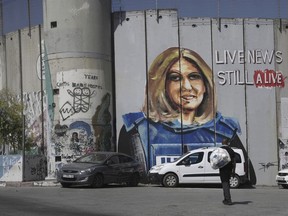 A man walks near a mural depicting slain Palestinian American journalist Shireen Abu Akleh, on Israel's controversial separation barrier in the West Bank city of Bethlehem, Wednesday, July 6, 2022. The mural by Palestinian artist Taqi Spateen appeared early Wednesday, days ahead of a visit by U.S. President Joe Biden.