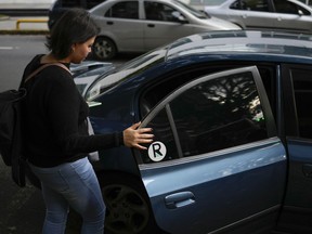 Department store buyer Maria Arreaza gets in a Ridery car she requested, outside her work in Caracas, Venezuela, Thursday, May 5, 2022. Arreaza, 39, had long depended on public transportation to reach her downtown office and was intrigued by advertisements for the new Ridery app, though initially skeptical, she is now a frequent user of Ridery.