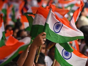 School students wave Indian national flags during the celebrations to mark India's 75th Independence Day at the Red Road in Kolkata on August 15, 2022. (Photo by Dibyangshu SARKAR / AFP)