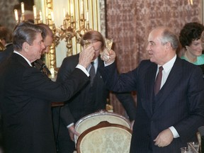 In this file photo taken on December 9, 1987 Soviet leader Mikhail Gorbachev (C) and US President Ronald Reagan (L) share smiles after toasting each other, during a dinner hosted by Gorbachev at the Soviet Embassy. (Photo by JEROME DELAY/AFP via Getty Images)
