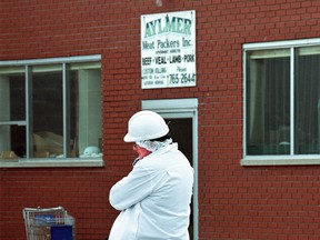An investigator speaks on a cellphone outside of the Aylmer Meat Packers Inc. plant on August 29, 2003.