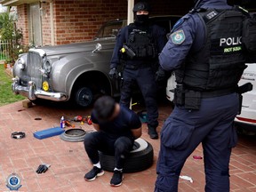 Polizeifotos von der Razzia zeigen die markanten Linien eines metallisch-silbernen Bentley in der Einfahrt eines Hauses unter einem offenen Carport.