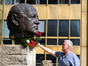 A man places a rose on a sculpture of Mikhail Gorbachev in memory of the final leader of the Soviet Union, at the "Fathers of Unity" memorial in Berlin, Germany, on Aug. 31, 2022.