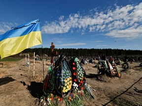 Ukraine's flag is seen beside new graves for people killed during Russia's invasion of Ukraine, at a cemetery in Bucha, Ukraine, April 28.