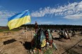 Ukraine's flag is seen beside new graves for people killed during Russia's invasion of Ukraine, at a cemetery in Bucha, Ukraine, April 28.