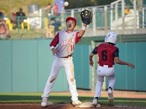Japan's Yujiro Kume (14) stretches for the ball as Canada's Omar Bousmina (6) beats out an infield single during the sixth inning of a baseball game at the Little League World Series tournament in South Williamsport, Pa., Friday, Aug. 19, 2022.