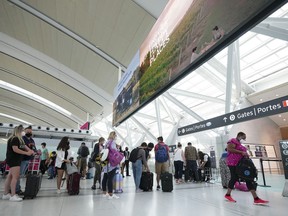 Die Menschen stellen sich am Freitag, den 5. August 2022, vor dem Betreten der Sicherheitskontrolle am Pearson International Airport in Toronto an.