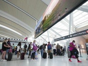 People line up before entering the security at Pearson International Airport in Toronto on Friday, August 5, 2022.