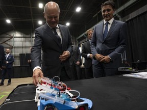 Canadian Prime Minister Justin Trudeau looks on as German Chancellor Olaf Scholz examines a hydrogen powered model car as they tour a trade show, Tuesday, August 23, 2022 in Stephenville, Newfoundland and Labrador.