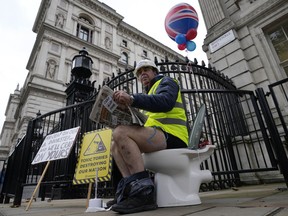 FILE - An activist sits on a toilet at the entrance to Downing Street to protest against raw sewage dumping in the rivers and seas around the UK in London, on Oct. 26, 2021. EU lawmakers have a new, post-Brexit reason to be annoyed with Britain: British sewage overflows seeping into the English Channel and North Sea.