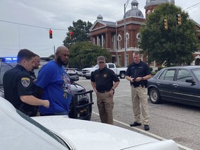 This photo provided by Troup County Sheriff's Office police take Jerel Raphael Brown into custody on Aug. 17, 2022 in LaFayette, Ala. Brown, 39, of Montgomery was arrested without incident Wednesday near the courthouse in LaFayette with more than 2,000 rounds of ammunition and an alarming number of firearms in his 1996 white Cadillac Fleetwood, police said. (Troup County Sheriff's Office via AP)