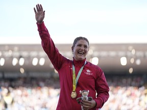 Sarah Mitton of Canada smiles on the podium after winning the gold medal in the Women's shot put during the athletics competition in the Alexander Stadium at the Commonwealth Games in Birmingham, England, Thursday, Aug. 4, 2022.