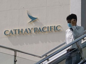 FILE - A man walks at the Cathay City, the headquarters of Hong Kong airline Cathay Pacific Airways, in Hong Kong, Wednesday, Oct. 21, 2020. The airline said Wednesday, Aug. 10, 2022, that losses in the first half of the year narrowed as a relaxation in quarantine rules boosted passenger numbers.