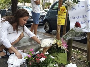 FILE - A woman places a bouquet of flowers where Nigerian street vendor Alika Ogorchukwu was murdered, in Civitanova Marche, Italy, Saturday, July 30, 2022. A judge in Italy on Monday ordered an Italian man to remain jailed as an investigation continues into the brutal beating of Ogorchukwu, a slaying that shocked many in Italy and provoked the condemnation of the Nigerian government.