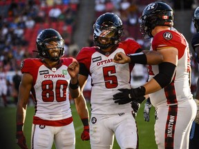 Ottawa Redblacks quarterback Caleb Evans (5) celebrates with teammates wide receiver Nate Behar (80) and offensive lineman Connor Berglof (59) after Evans ran the ball forward during fourth quarter CFL action against, in Toronto on Sunday July, 31, 2022.