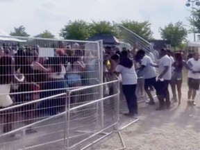 Security personnel try to stop concertgoers from crashing through a fence at the Kingston Music Festival in Toronto's Downsview Park.