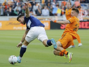 Vancouver Whitecaps forward Lucas Cavallini, left, and Houston Dynamo midfielder Griffin Dorsey fall while competing for the ball during the first half of an MLS soccer match Saturday, March 12, 2022, in Houston.