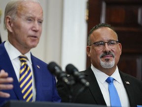 Education Secretary Miguel Cardona listens as President Joe Biden speaks about student loan debt forgiveness in the Roosevelt Room of the White House, Wednesday, Aug. 24, 2022, in Washington.