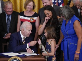 President Joe Biden gives the pen he used to sign the "PACT Act of 2022" to Brielle Robinson, daughter of Sgt. 1st Class Heath Robinson, who died of cancer two years ago, during a ceremony in the East Room of the White House, Wednesday, Aug. 10, 2022, in Washington.