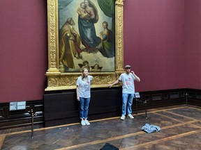 In this photo provided by the climate activist group 'Letzte Generation', Last Generation, shows activist glued themselves to the frame of the painting 'Sistine Madonna' by Raffael at the Gemaeldegalerie Museum in Dresden, Germany, Tuesday, Aug. 23, 2022.