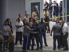 Police officers and other officials stand outside the Ryder Trauma Center after a Miami-Dade police officer was shot in an exchange of gunfire during a car chase with an armed robbery suspect, Monday, Aug. 15, 2022, in Miami.