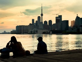 People sit and watch storm clouds passing by the skyline in Toronto on Tuesday, June 8, 2021.