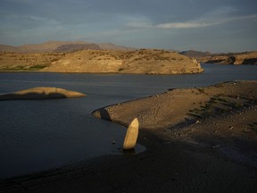 FILE - A formerly sunken boat sits upright into the air with its stern stuck in the mud along the shoreline of Lake Mead at the Lake Mead National Recreation Area, on June 10, 2022, near Boulder City, Nev. Authorities in Las Vegas have identified bones found in May along newly exposed Lake Mead shoreline as the remains of a 42-year-old Las Vegas man who is believed to have drowned 20 years ago. The Clark County coroner's office said Wednesday, Aug. 24, 2022, that Thomas Erndt was reported missing in August 2002.