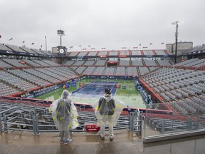 Volunteers wear rain jackets as rain falls on centre court at the National Bank Open tennis tournament in Montreal, Monday, August 8, 2022.