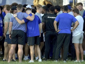 Members of the Indiana State football team console one another after a vigil at Memorial Stadium in Terre Haute, Ind., on Sunday, Aug. 21, 2022, for students, including fellow football players, who were involved in a car crash earlier in the day.