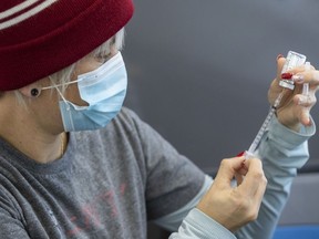 Clinic volunteer Kelly Brown draws out Moderna vaccine during a drive through COVID-19 vaccine clinic at St. Lawrence College in Kingston, Ont., on January 2, 2022.