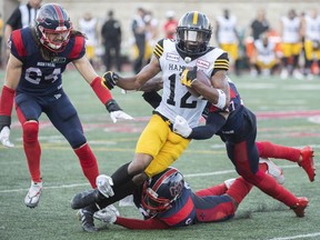 Hamilton Tiger-Cats' Tim White (12) is brought down by Montreal Alouettes defence during second half CFL football action in Montreal on August 20, 2022. White, B.C. linebacker Obum Gwacham and Montreal quarterback Trevor Harris have been named the CFL's top performers for Week 11 of the 2022 season.