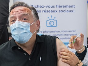 Quebec Premier François Legault receives a COVID-19 booster vaccine dose from Kenza Kias in Montreal on Aug. 5, 2022. Quebec is launching a massive COVID-19 booster vaccine campaign as health officials expect cases to go up in the fall with students returning to school.