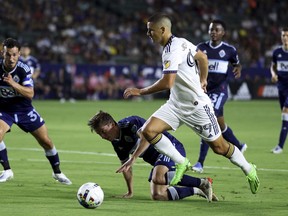 LA Galaxy forward Dejan Joveljic, right, hops over Vancouver Whitecaps midfielder Ryan Gauld during the second half of an MLS soccer match on August 13, 2022, in Carson, Calif.