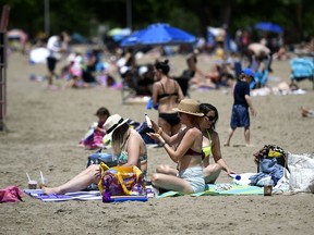 People apply sunscreen as they enjoy the warm weather at Mooney's Bay Beach in Ottawa, on Saturday, June 12, 2021.