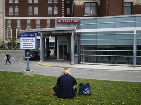 A person rests on a lawn outside the Emergency Department entrance at the Ottawa Hospital Civic Campus in Ottawa is shown on Monday, May 16, 2022. A new survey suggests there is a significant decrease in the well-being of physicians across Canada as many doctors report their mental health is worse than before the COVID-19 pandemic.