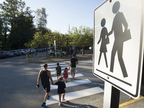 Children walk with their parents to Sherwood Park Elementary in North Vancouver for their first day back to school on Sept. 10, 2020. Masks remain optional in newly released British Columbia guidelines for schools, but some teacher and parent groups are seeking more stringent COVID-19 protocols.