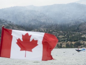 Boaters enjoy Skaha Lake as a wildfire burns in the background in Penticton, B.C. Thursday, August 20, 2020.THE CANADIAN PRESS/Jonathan Hayward