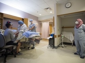 A nurse wearing a protective face mask looks on as Kate Chong receives an epidural from the on call anesthesiologist at St. Paul's hospital in downtown Vancouver, Saturday, June 13, 2020. Several Ontario hospitals say they are preparing for a potential shortage of epidural catheters as the province takes steps to track the inventory of the devices used to provide anesthesia during childbirth and some surgeries.