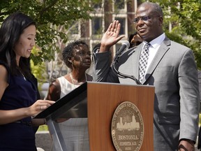 Michael Cox, right, raises his hand as he is sworn in as commissioner of the Boston police department by Mayor Michelle Wu, left, Monday, Aug. 15, 2022, in Boston. Cox, a Boston police veteran, was brutally beaten by fellow officers while chasing a suspect and fought against efforts to cover up his assault.