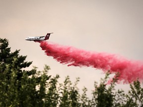 A plane dumps fire retardant to contain the Elmo Fire burning on the western shore of Flathead Lake, Mont., on Monday, Aug. 1, 2022.