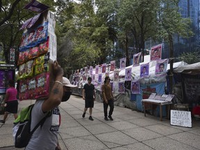 Pedestrians walk past posters dedicated to the 2014 disappearances of 43 students from a Guerrero state radical teacher college, in Mexico City, Saturday, Aug. 20, 2022. Prosecutors say they have arrested a former attorney general and issued warrants for dozens of army soldiers and officers, police and gang members in the disappearance of the students.