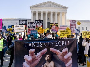 FILE -Stephen Parlato of Boulder, Colo., holds a sign that reads "Hands Off Roe!!!" as abortion rights advocates and anti-abortion protesters demonstrate in front of the U.S. Supreme Court, Wednesday, Dec. 1, 2021, in Washington. With abortion now or soon to be illegal in over a dozen states and severely restricted in many more, Big Tech companies that collect personal details of their users are facing new calls to limit that tracking and surveillance.