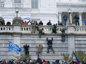 FILE - Violent insurrectionists loyal to President Donald Trump climb the west wall of the U.S. Capitol in Washington, Jan. 6, 2021. Federal prosecutors on Tuesday, Aug. 9, 2022, are recommending a sentence of six months' probation for a former Virginia police officer who pleaded guilty to storming the U.S. Capitol with another off-duty officer.