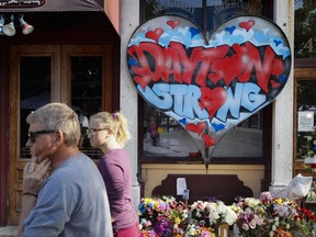 FILE - In this Aug. 7, 2019 file photo, pedestrians pass a makeshift memorial for the slain and injured victims of a mass shooting that occurred in the Oregon District in Dayton, Ohio. The six officers who shot and killed an active shooter in Dayton 32 seconds after the man's assault began have offered brief comments about that night for the first time. The officers' remarks are coming on the eve of the third anniversary of the massacre that killed nine and wounded more than two dozen.