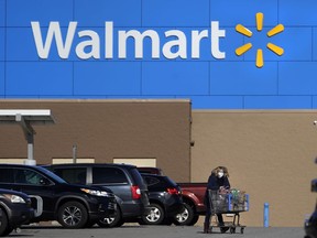 FILE - A woman wheels a cart with her purchases out of a Walmart, on Nov. 18, 2020, in Derry, N.H. Walmart, the nation's largest employer, is expanding its abortion coverage for employees, according to a memo sent to employees Friday, Aug. 19, 2022, after staying mum on the topic for months following the Supreme Court ruling that scrapped a nationwide right to abortion.